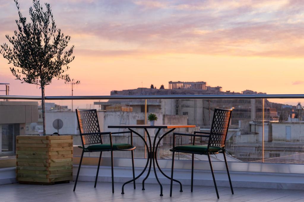 een tafel en stoelen op een balkon met uitzicht op de stad bij Hestia - Ippokratous 35 in Athene