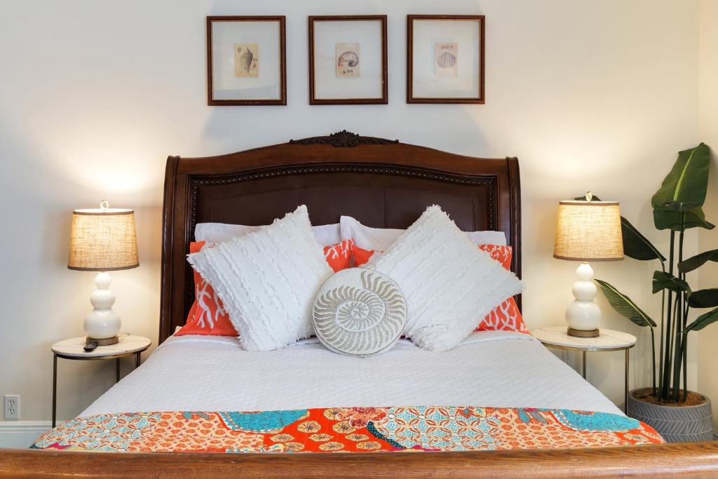 a bed with orange and white pillows and two lamps at Studio Blue in Key West