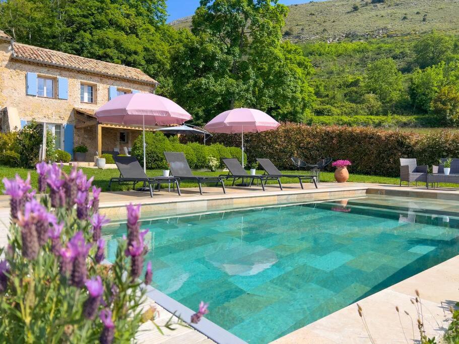 a pool with chairs and umbrellas and a house at Mas provençal avec piscine in Tourrettes-sur-Loup