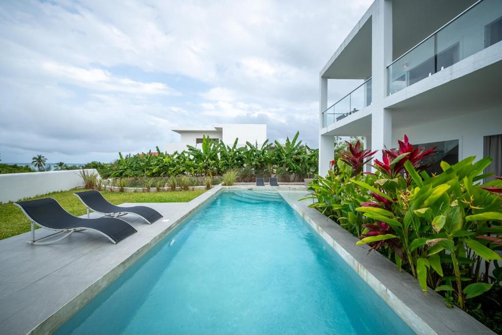 una piscina con 2 sillas y una casa en OceanView Villa Manzini with Private Pool ZanzibarHouses en Kiwengwa