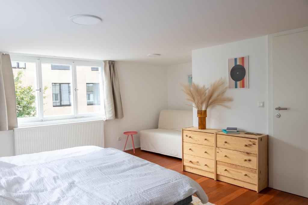 a white bedroom with a bed and a dresser at Wohnperle im pulsierenden Dornbirn - Ibiza 3 in Dornbirn