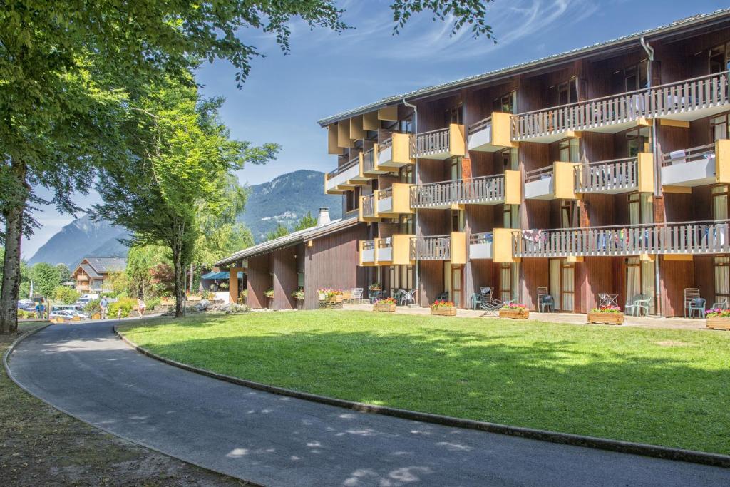 a building with a green lawn in front of it at AEC Vacances - Les Becchi in Samoëns