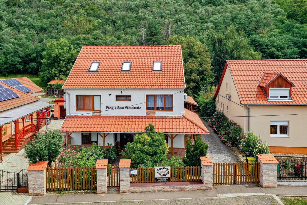 a house with an orange roof and a fence at Fekete Rigó Vendégház in Egerszalók