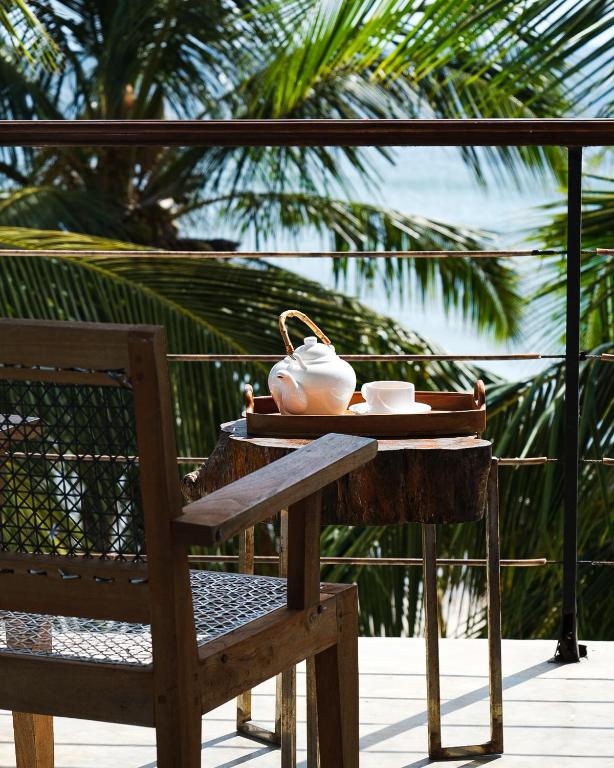 a tea pot sitting on a table next to a chair at Cardamon Hotel Nilaveli in Nilaveli