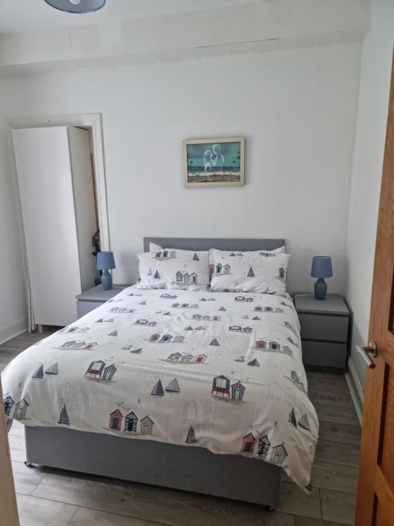 1 dormitorio con 1 cama grande con edredón y almohadas en Lido Bay Ground Floor Apartment en Largs