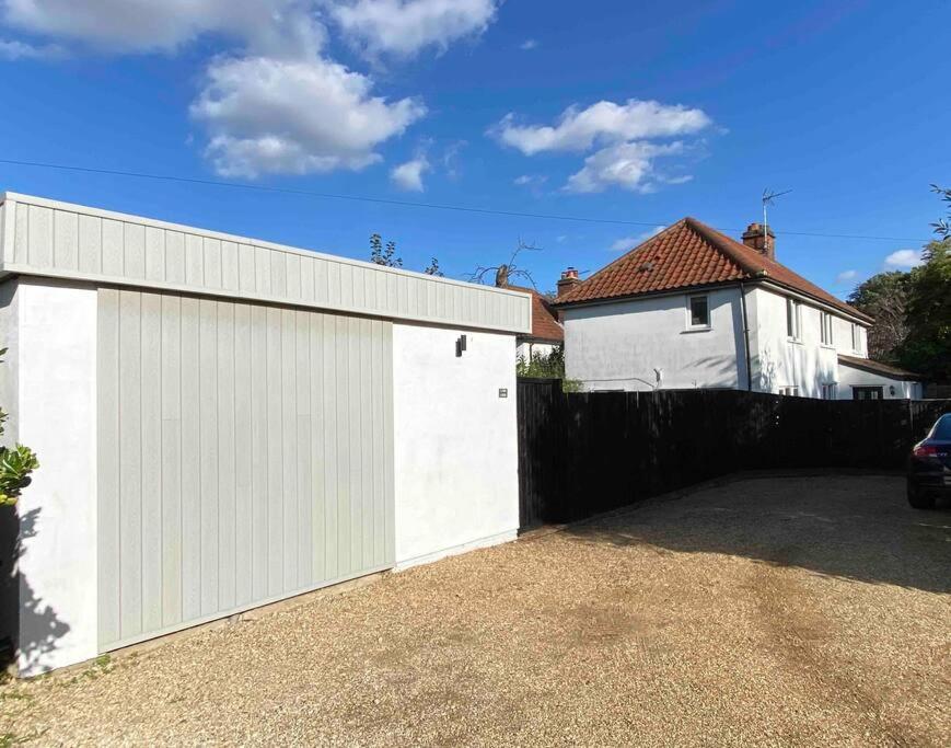 a white garage with a fence and a house at Lumin Lodge -Calm, cosy space near Norwich Airport in Horsham Saint Faith