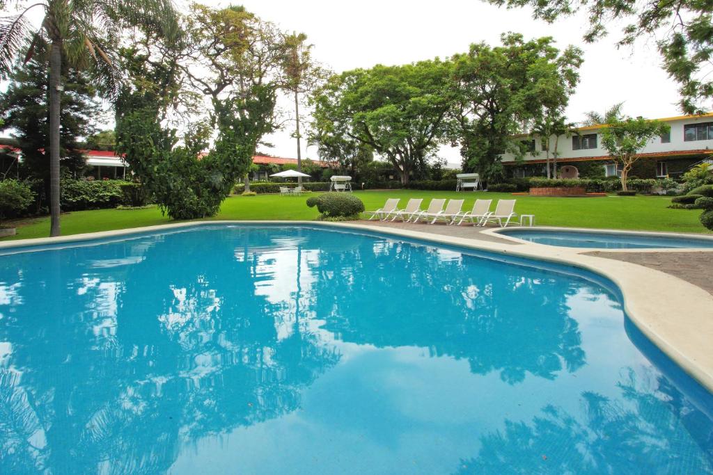 uma grande piscina com água azul num quintal em Hotel Posada Quinta Las Flores em Cuernavaca