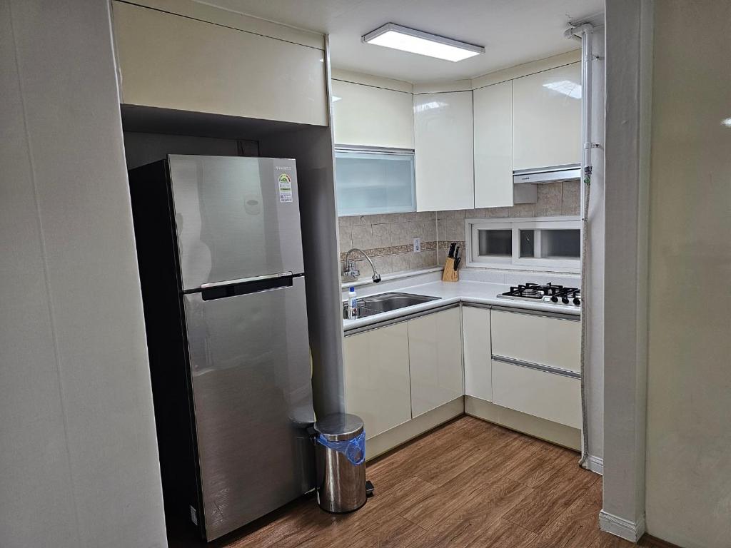 a kitchen with white cabinets and a stainless steel refrigerator at Byeongjeom-yeok Stay 