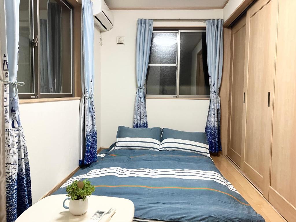 Ce lit se trouve dans une petite chambre dotée de rideaux bleus. dans l'établissement 新規OPEN8割！1棟貸切・10名可能！秋葉原まで13分、新宿まで32分／スカイツリー近く, à Tokyo