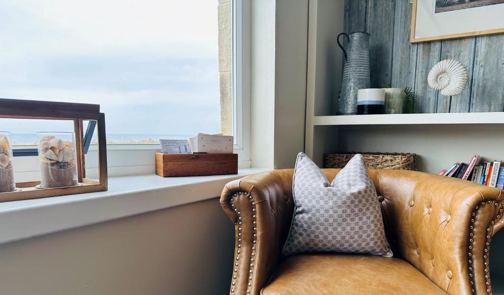 a couch sitting next to a window with a mirror at Beach House Hotel in Seahouses