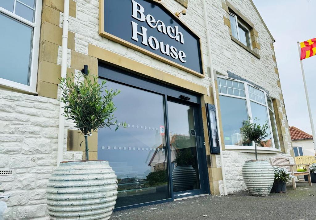 a store with two large vases in front of a building at Beach House Hotel in Seahouses