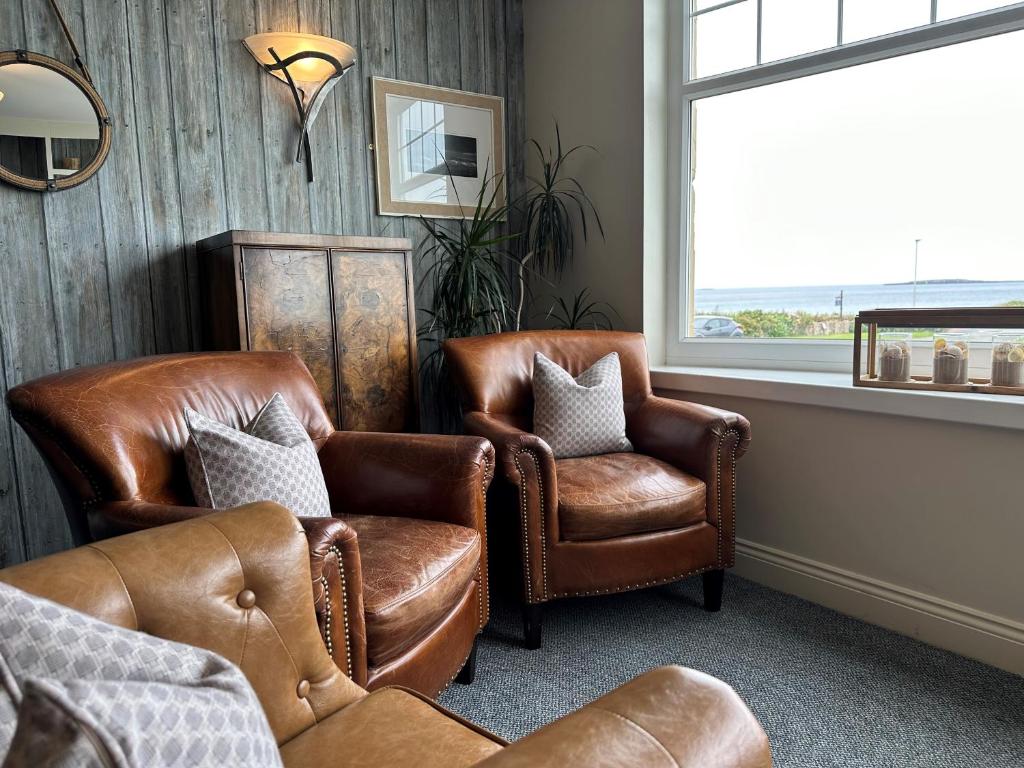 a living room with two leather chairs and a window at Beach House Hotel in Seahouses