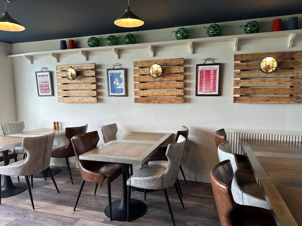 a dining room with wooden tables and chairs at Beach House Hotel in Seahouses