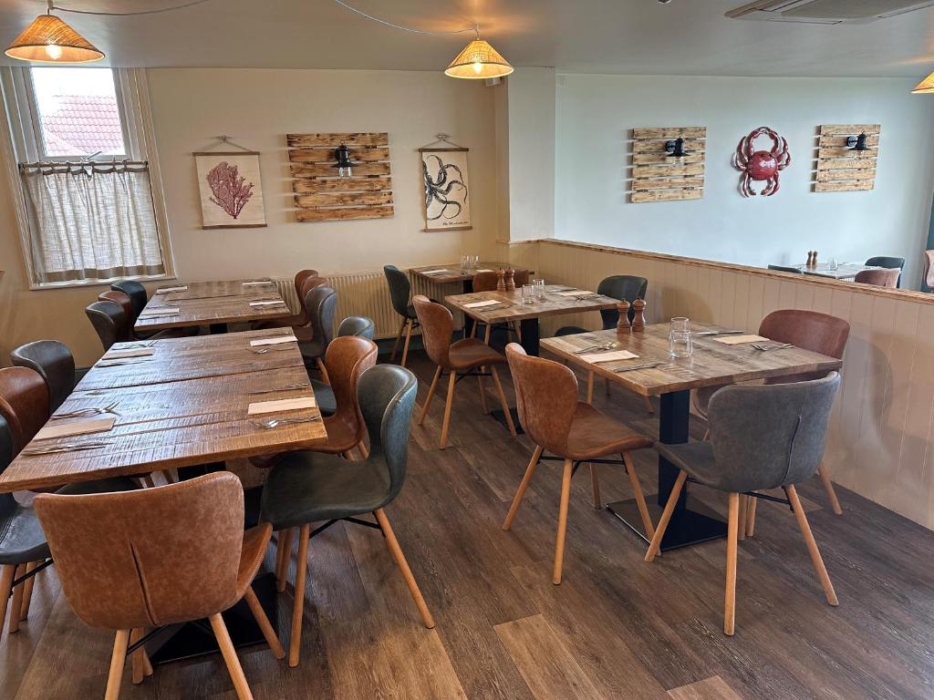 a dining room with wooden tables and chairs at Beach House Hotel in Seahouses
