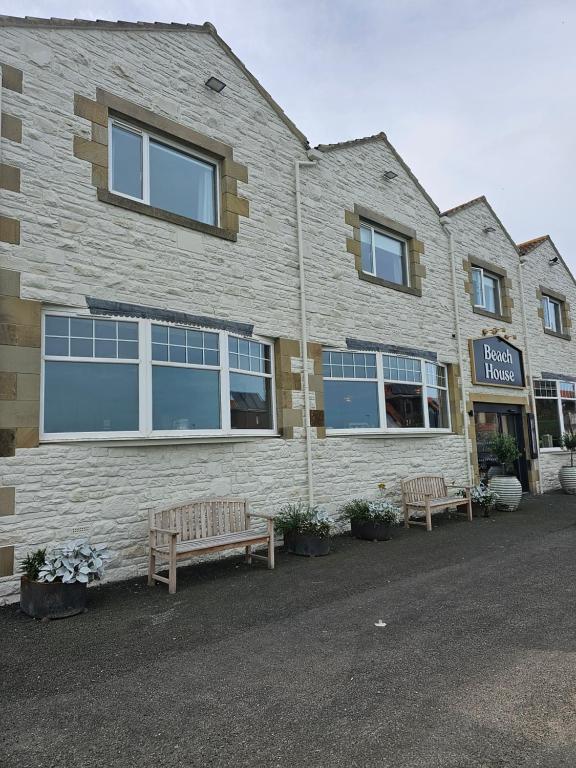 a building with two benches in front of it at Beach House Hotel in Seahouses