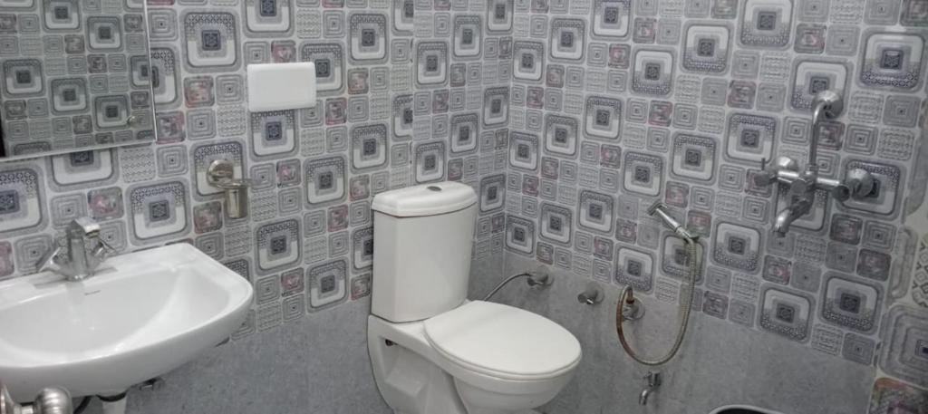 a bathroom with a toilet and a sink with a wallpaper at Kailash Haveli in Bikaner