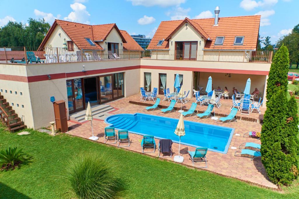 a house with a swimming pool with chairs and umbrellas at Boni Családi Wellness Hotel in Zalakaros