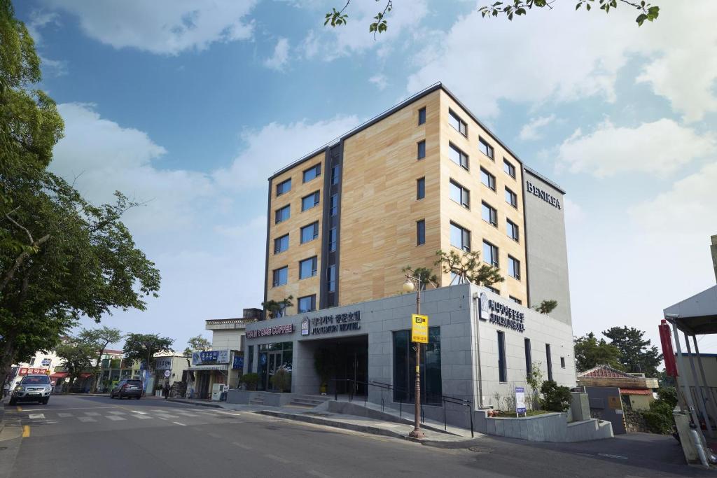 a tall building on a street with a street at Benikea Jungmun Hotel in Seogwipo