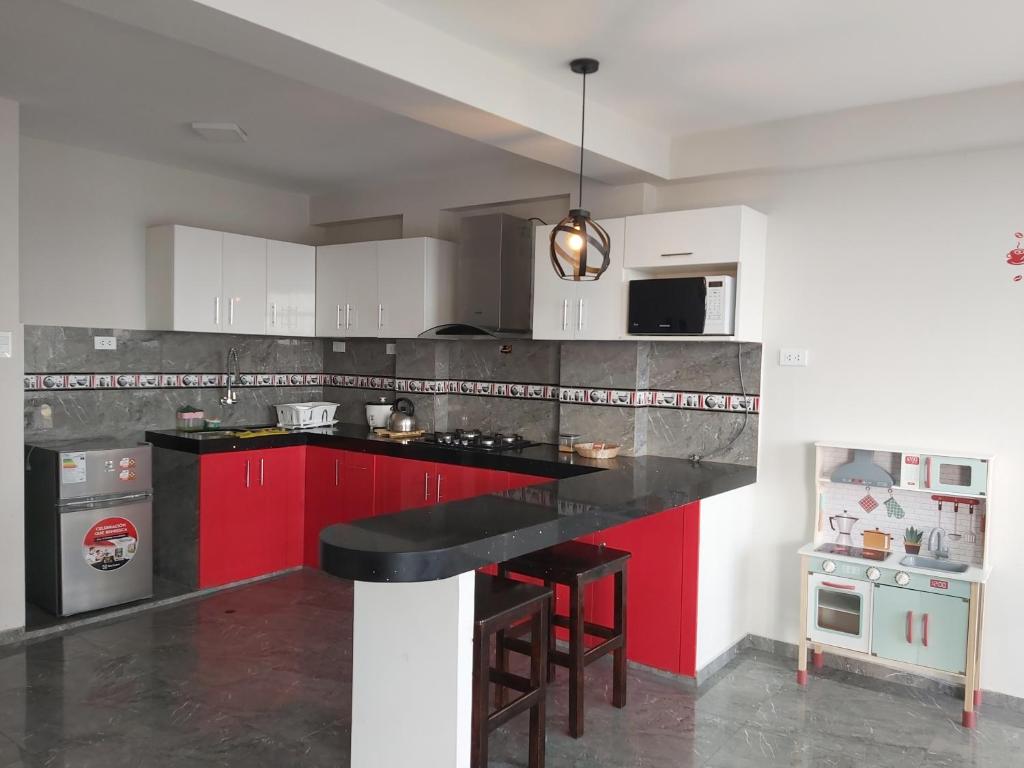 eine Küche mit roten Schränken und einer schwarzen Arbeitsplatte in der Unterkunft Apartamentos "APPART D'ELIETTE" in Trujillo