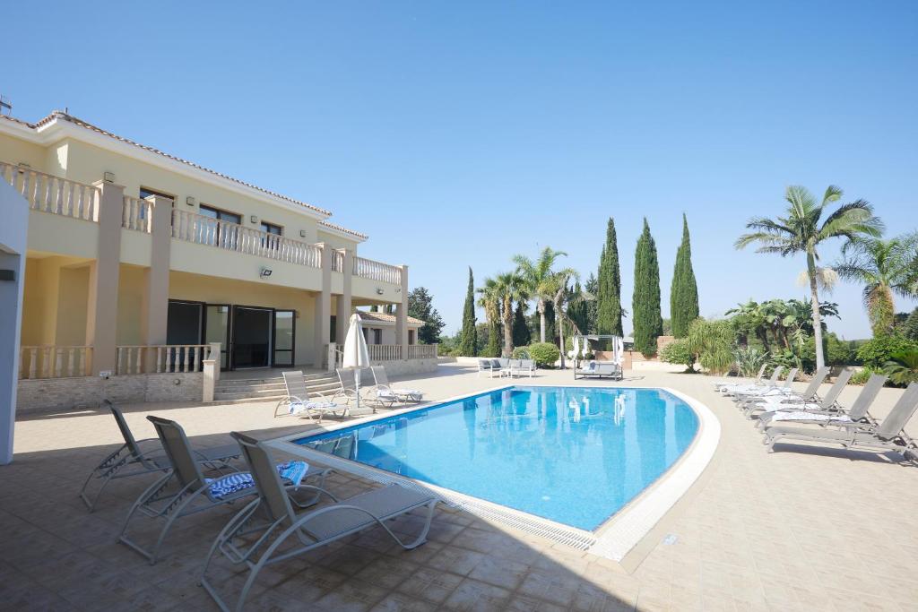 a large swimming pool with chairs and a building at Sparta Luxury Villa in Protaras