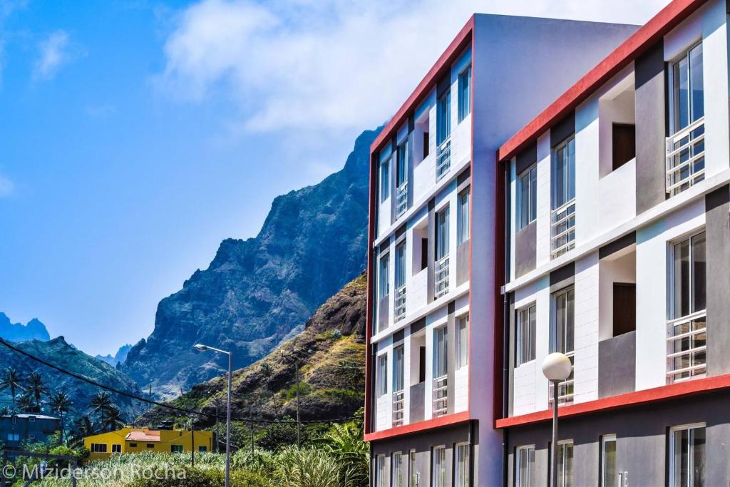 a red and white building with mountains in the background at Apartamento Santos in Ribeira Grande
