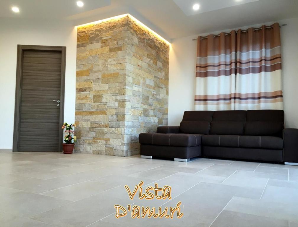 salon z kanapą i kamienną ścianą w obiekcie VISTA D'AMURI w mieście Sciacca