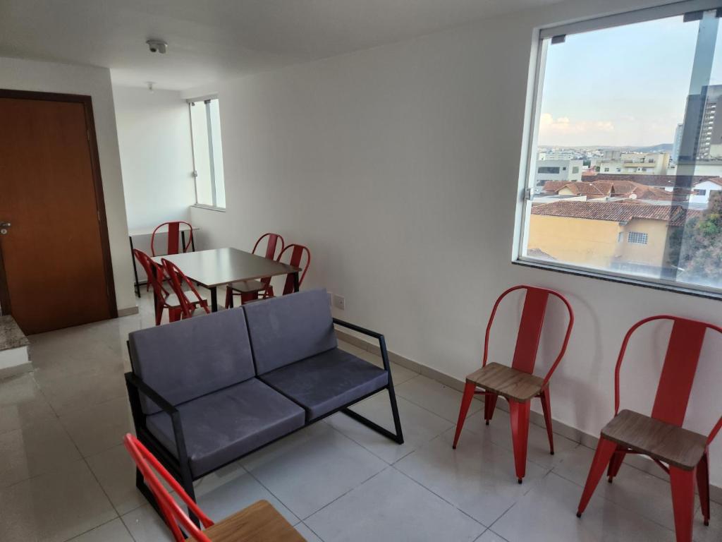 una sala de espera con sillas, una mesa y una ventana en Comfort 302 - 4 Quartos no Centro en Sete Lagoas