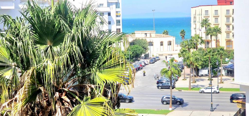 una calle de la ciudad con una palmera y el océano en Complejo al andalous Apartamento, en Tánger