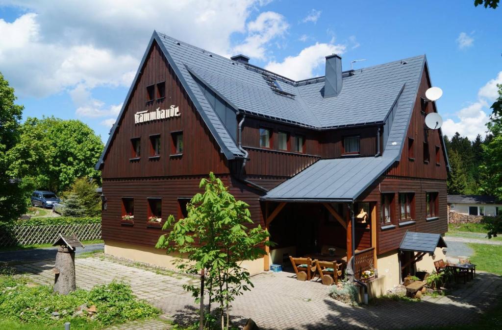 un grand bâtiment en bois avec un toit noir dans l'établissement Kammbaude Neuhermsdorf, à Neuhermsdorf