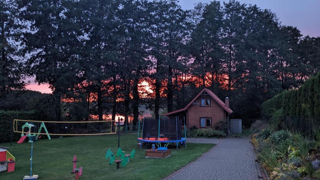 um quintal com parque infantil com casa e árvores em Domki u Jacka em Wilkasy