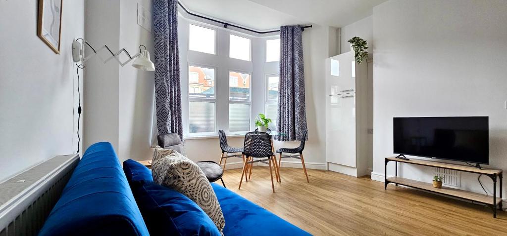 Harlequin Apartments by Switchback Stays في كارديف: غرفة معيشة مع أريكة زرقاء وتلفزيون
