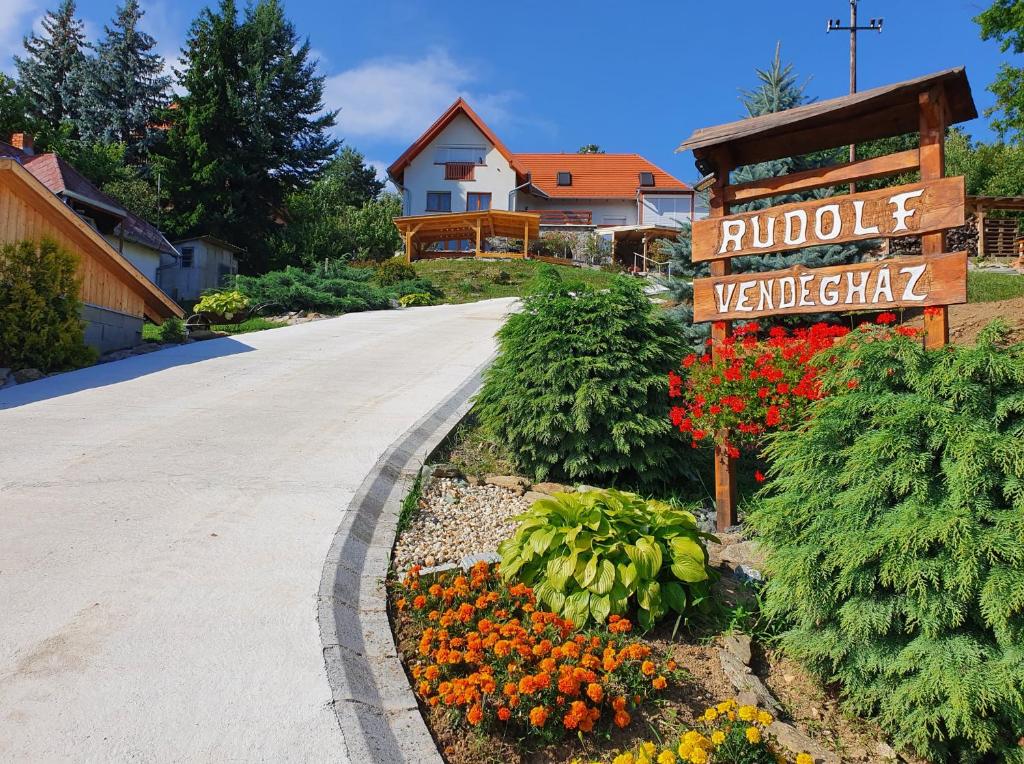 eine Einfahrt mit Schild und Blumen im Hof in der Unterkunft Rudolf Vendégház in Velem