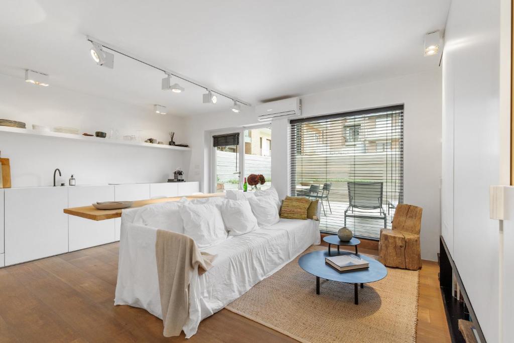 ein Wohnzimmer mit einem weißen Sofa und einem Tisch in der Unterkunft Julias Studio Stay in Knokke-Heist