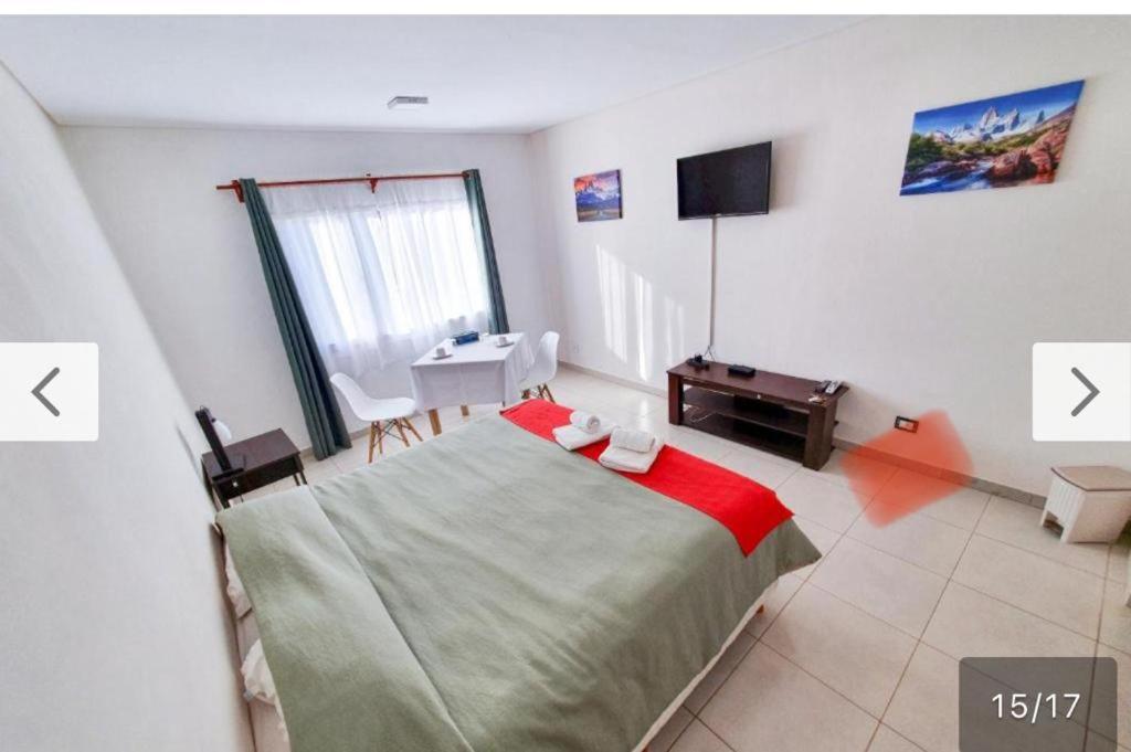 a bedroom with a bed and a table and a television at Newen Bed and breakfast in El Chalten