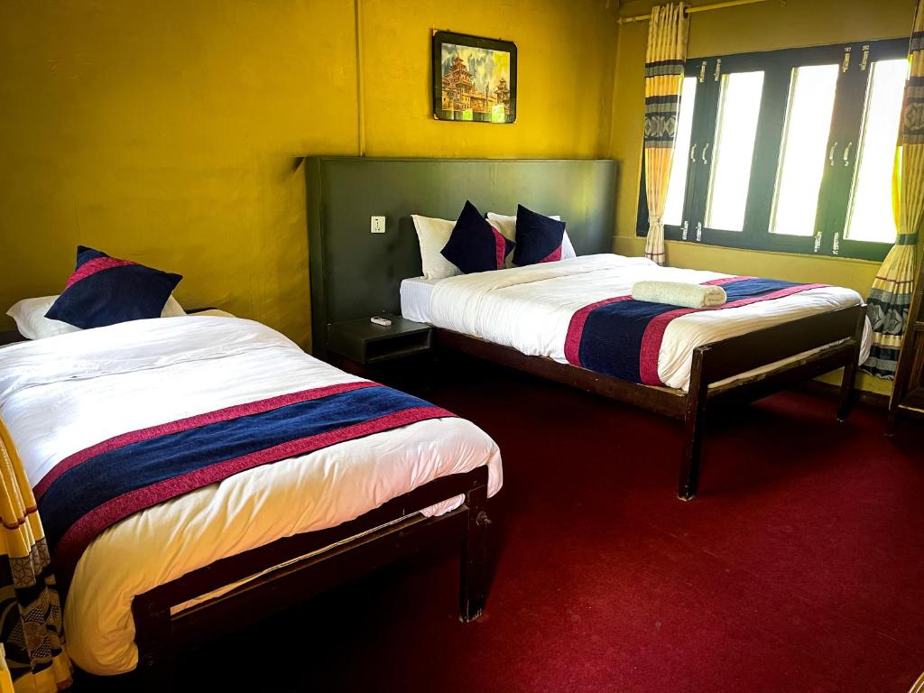 a bedroom with two beds and a red carpet at Hotel Tharu Garden And Beer Bar in Chitwan
