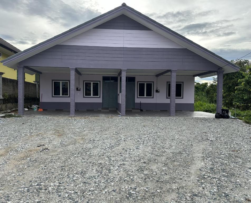 uma pequena casa com uma entrada de cascalho em frente em Dhia Homestay2 em Macang