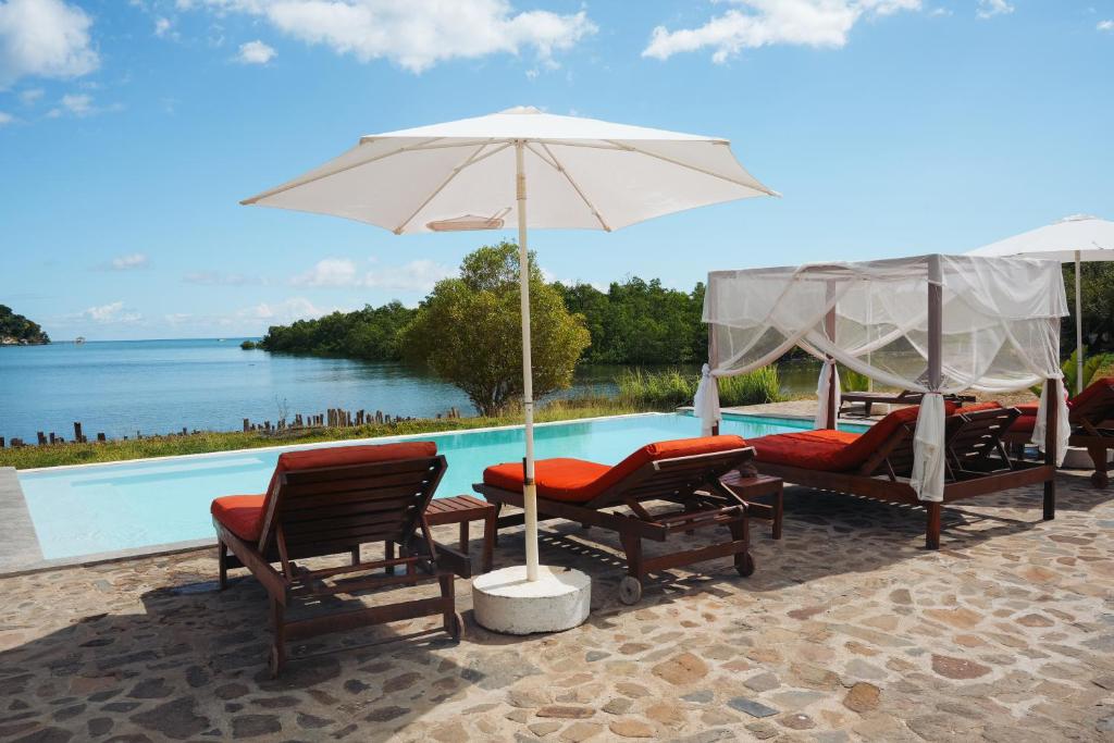 - un groupe de chaises et un parasol à côté de la piscine dans l'établissement Emeraude Lodge, à Andilana