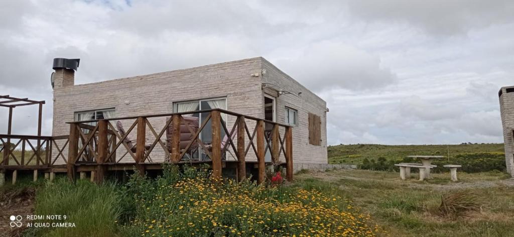 une maison avec une terrasse en bois dans un champ dans l'établissement Carabanchel, à Canepa