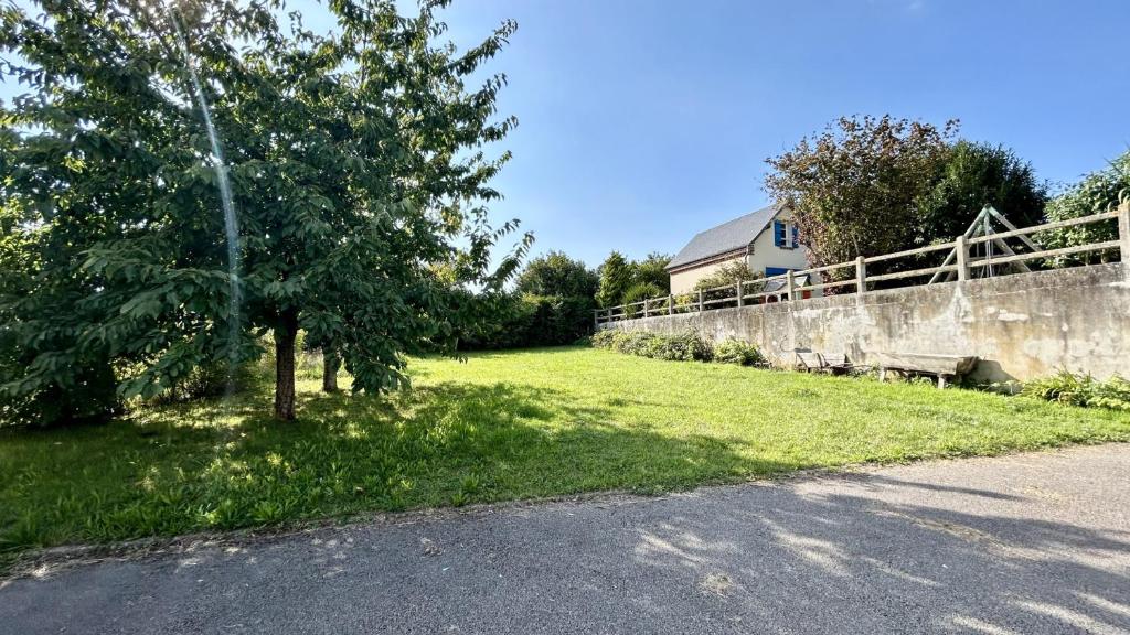 een boom in het gras naast een muur bij La Villa des Lilas in Saint-Valery-sur-Somme