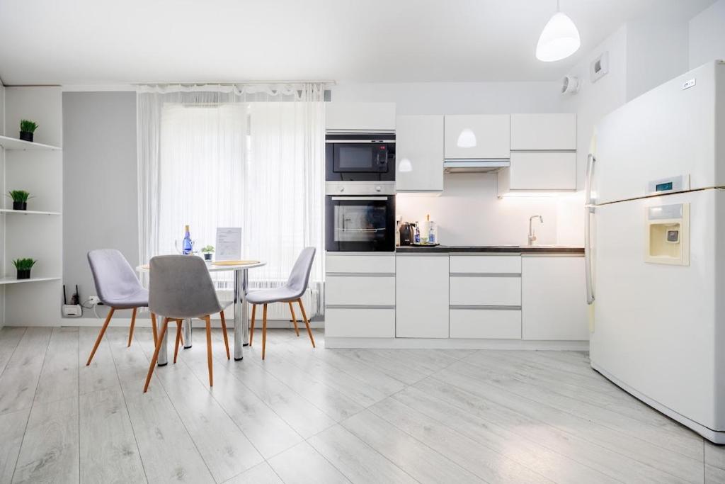 een keuken met witte kasten en een tafel en stoelen bij Apartamenty Zamkowe- High Standard Apartment in Rzeszów
