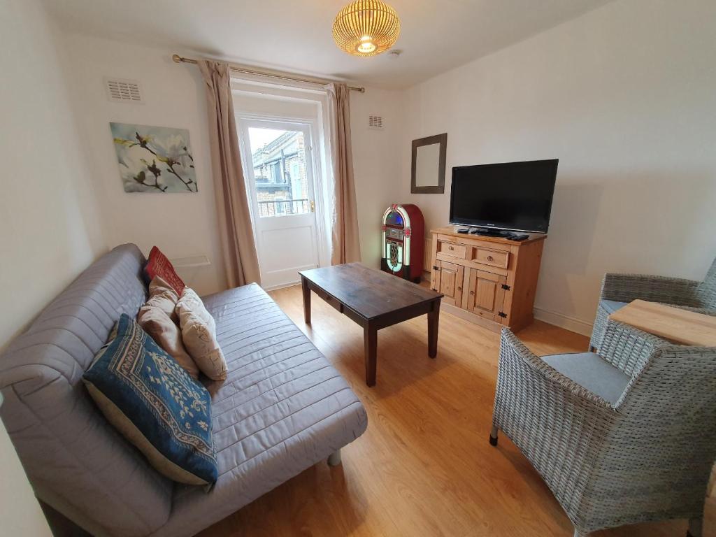 a living room with a couch and a television at 63B Willesden Lane Two Bed Apartment in London