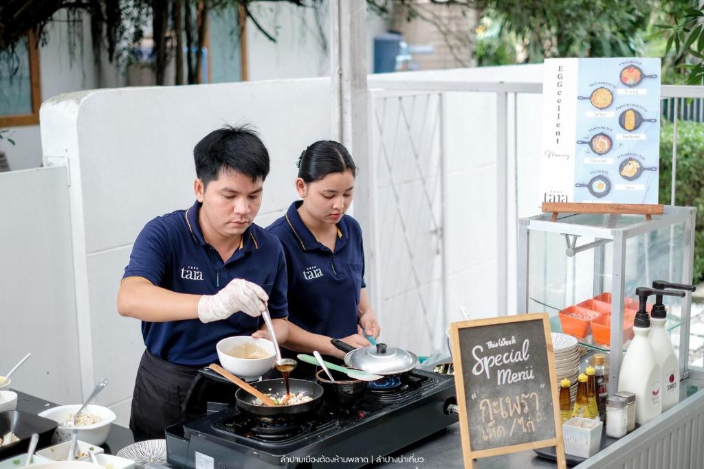 a couple of people cooking food on a grill at Tree Tara hotel in Lampang