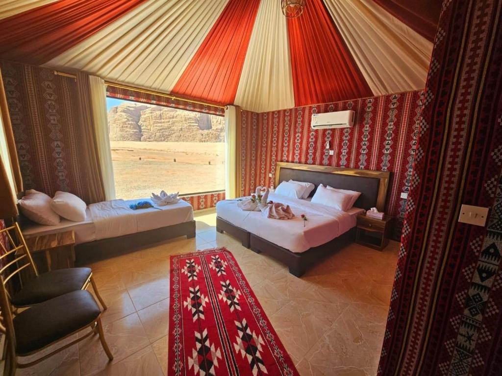 a bedroom with two beds and a large window at Hashem desert camp in Wadi Rum