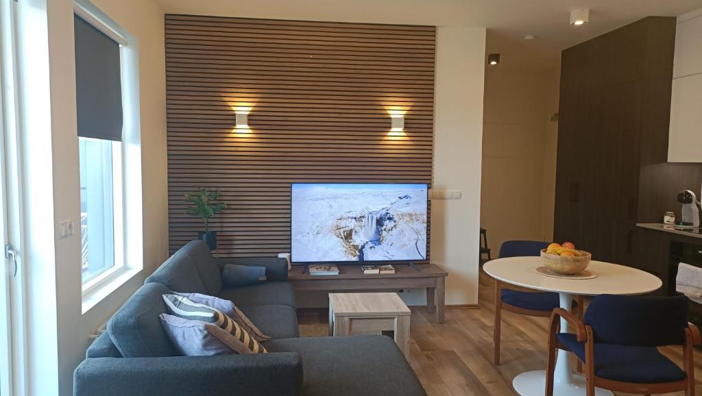 sala de estar con sofá azul y TV en Ocean View Suite near Sky Lagoon, en Reikiavik