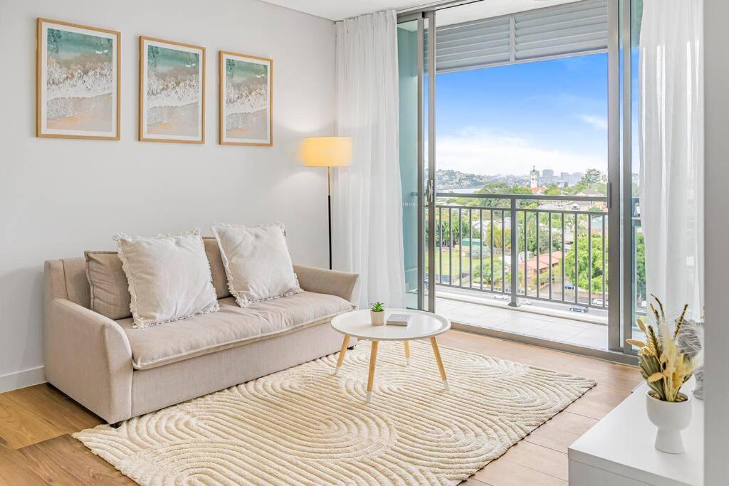 a living room with a couch and a large window at Bowen Hills 1 Bedroom Apartment in Brisbane