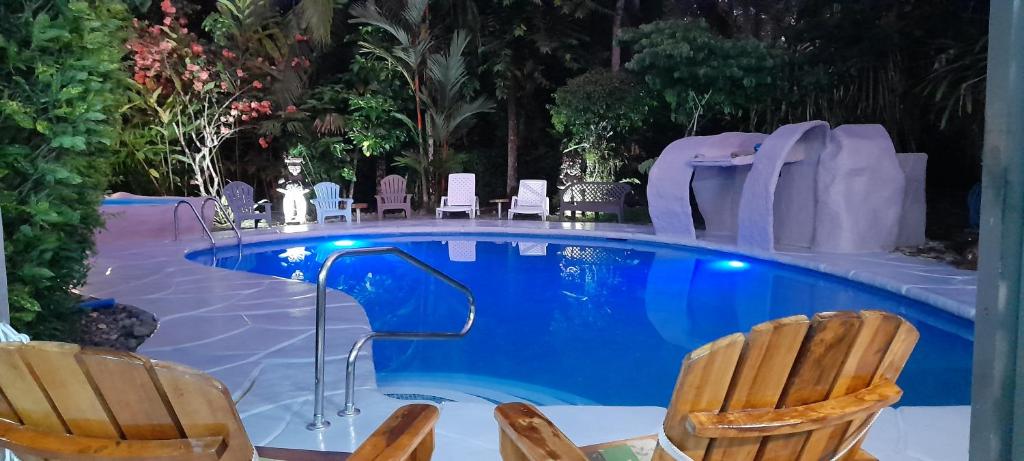 una piscina con due sedie e uno scivolo di Hotel El Colibri Rojo - Cabinas - Le Colibri Rouge a Cahuita