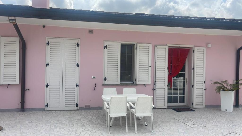 uma mesa e cadeiras em frente a uma casa rosa em Maison Valentina em Marendole