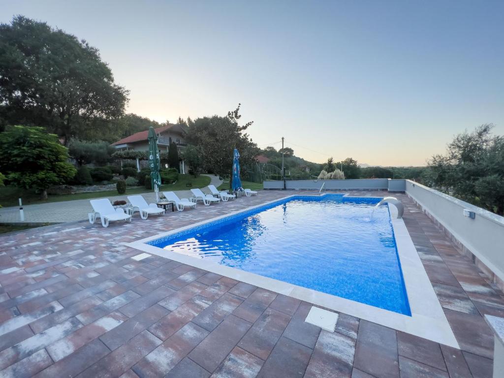 a swimming pool in a backyard with chairs and a swimming pool at Villa Ellie in Ljubuški