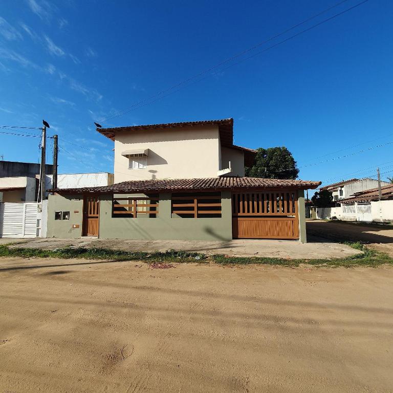 a white building with a brown door on a street at Apartamento Guriri Verão in São Mateus