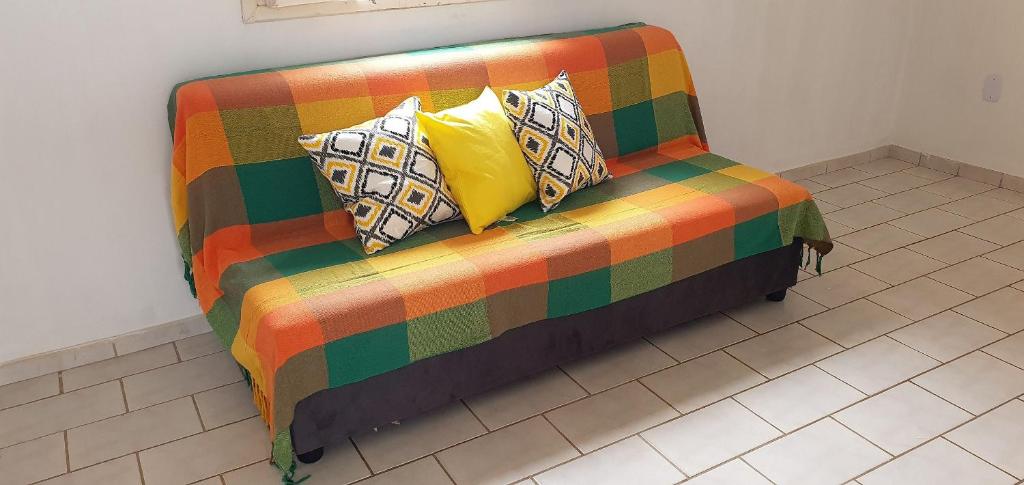 a colorful couch with pillows on a tile floor at Apartamento Guriri Verão in São Mateus